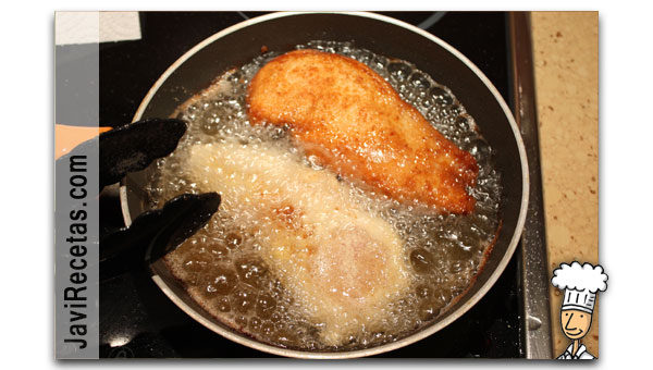Sartén con dos filetes de pollo empanado friéndose en aceite caliente