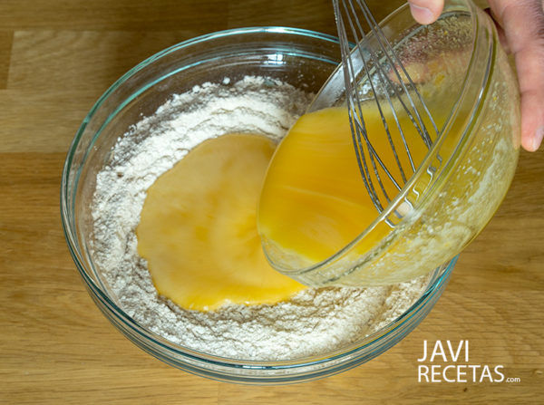 Volcando un cuenco con huevos, aceite y azúcar sobre otro con la harina